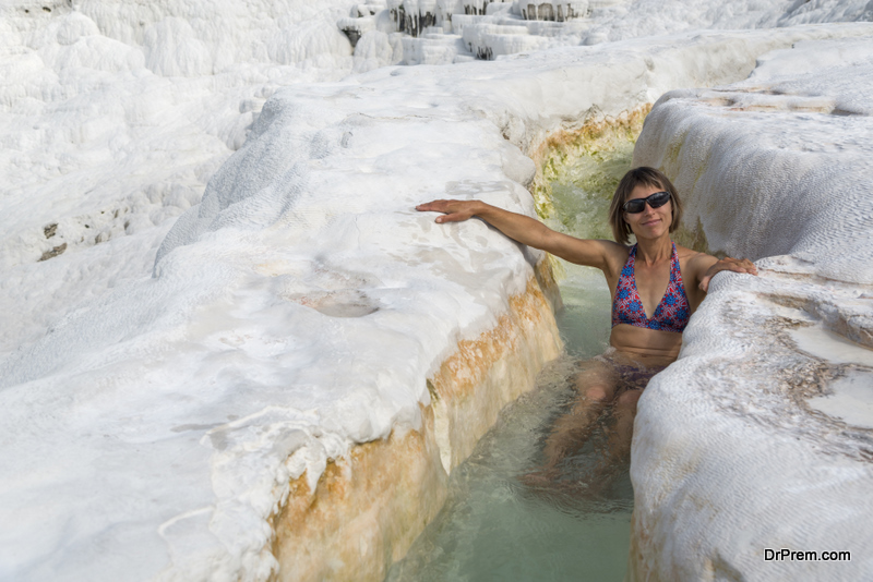 Woman in thermal river among whote rocks. Pamukkale travertine formations.