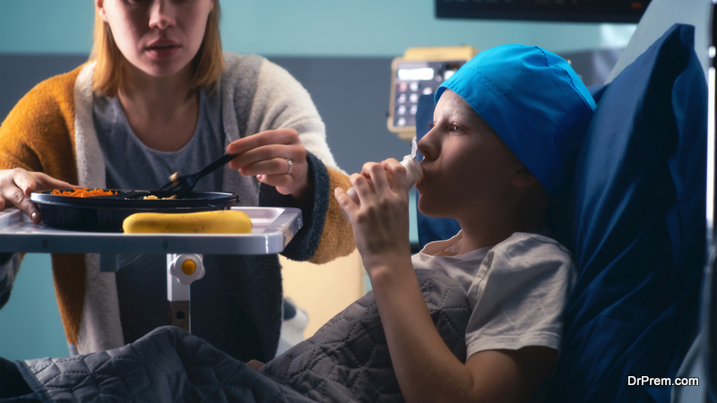 mother giving food to son while visiting cancer patient in oncology hospital ward