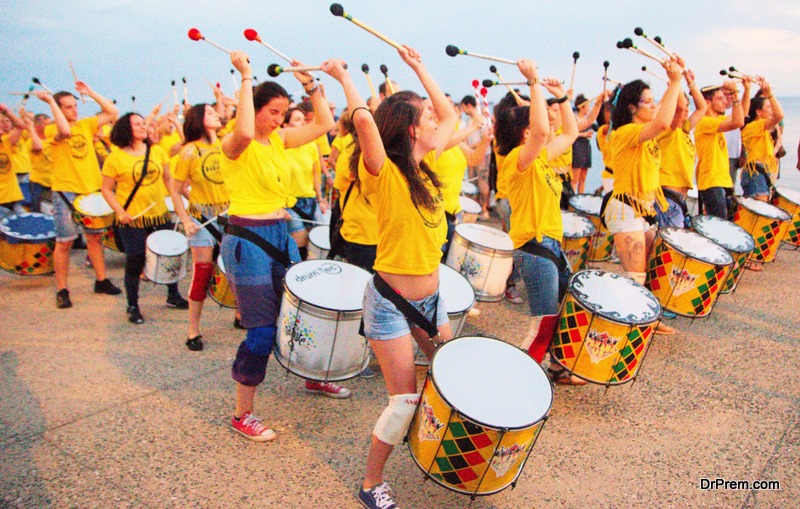 A picture of drummers in yellow skirts,playing music in the street in the towns center