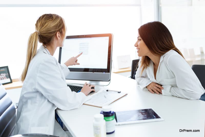 Shot of young woman gynecologist doctor showing to patient some information in computer in medical consultation.