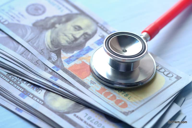 Stack of cash dollars and stethoscope on blue background.