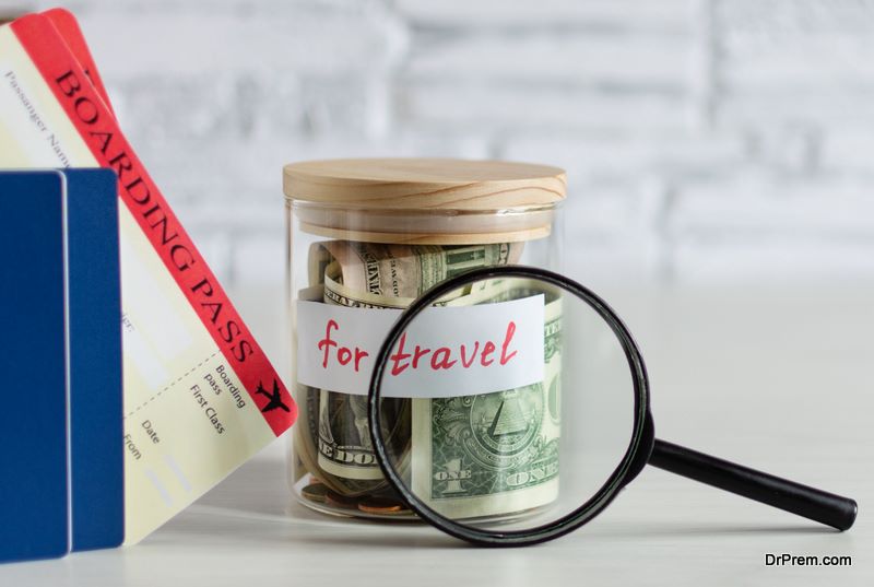 Money savings for travel in a glass jar on white wood table