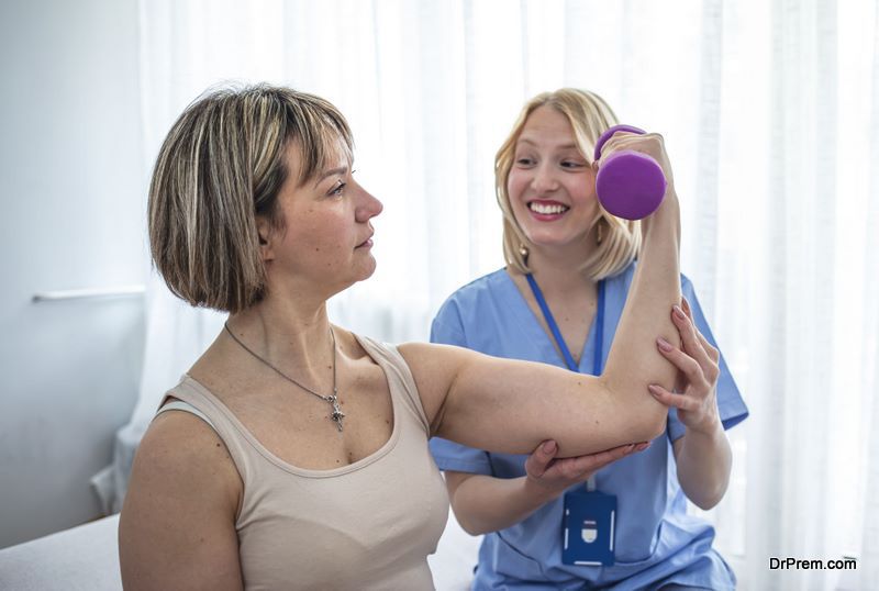 Woman physiotherapy professional giving a treatment to an mature client in a bright home