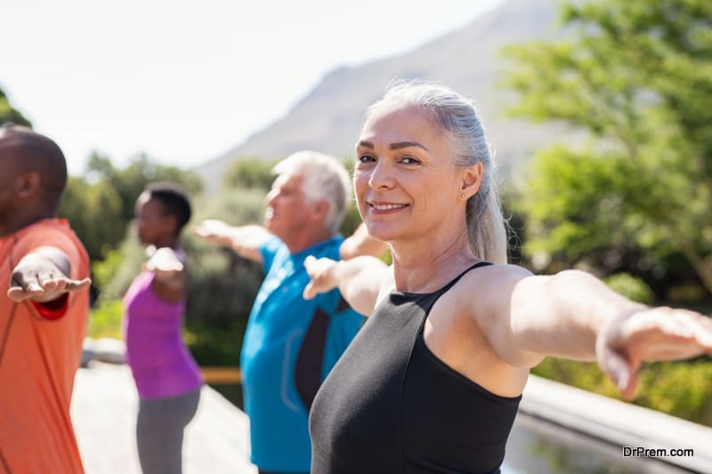 Portrait of happy senior woman practicing yoga outdoor with fitness class.
