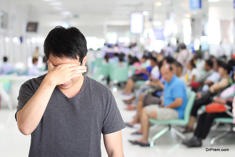 serious man holding his head, headache with blur hospital background