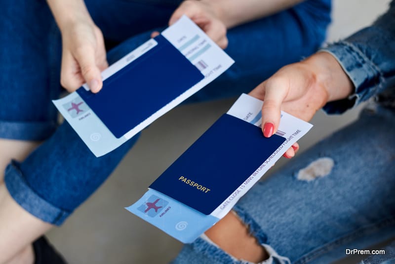 Close-up picture of female hands, holding blue international passports with boarding passes tickets inside. Air travel documents.