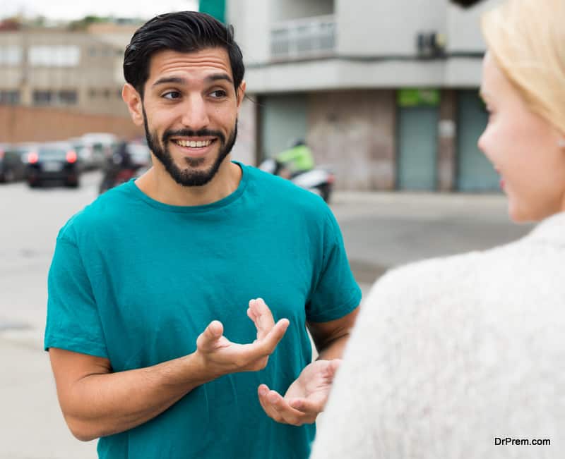 Female is talking with latino male in city.