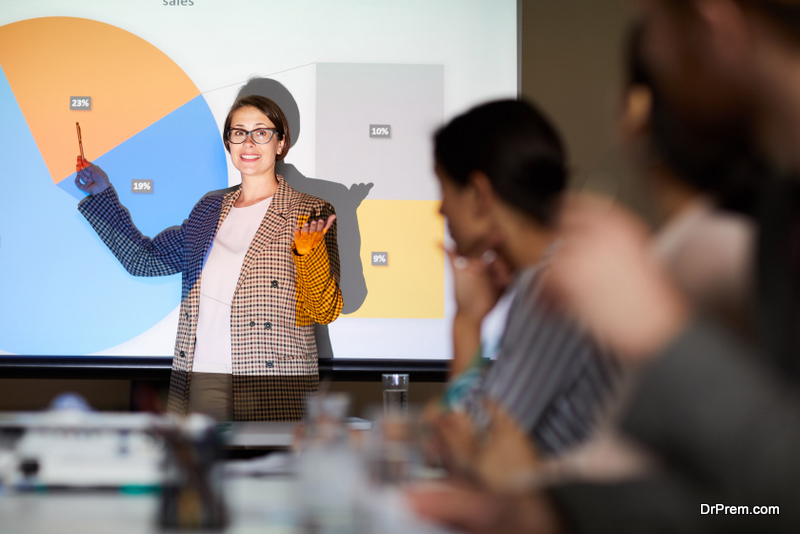 woman looking at audience standing against projector screen with data graph