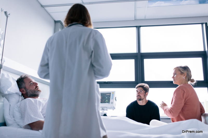 Male patient lying in hospital bed with his friends and doctor