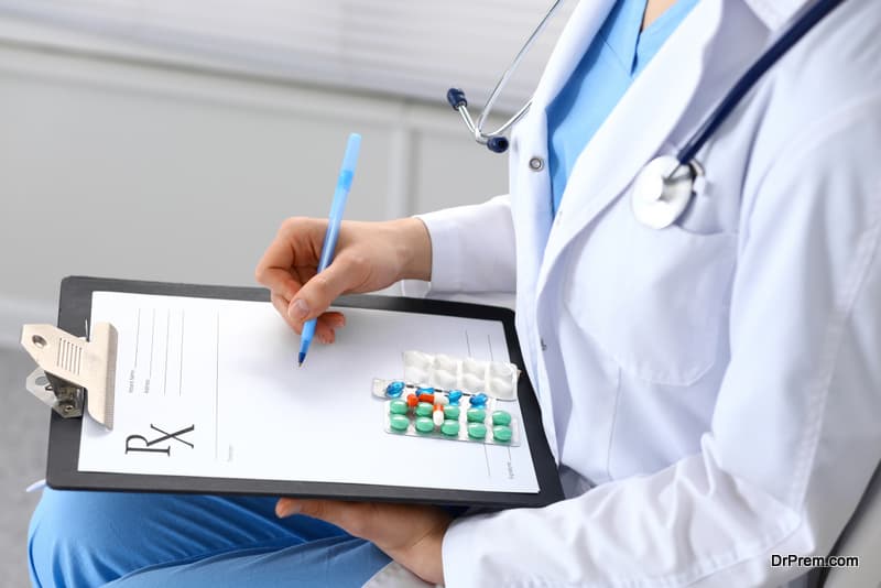 Young female physician write prescription or filling up medical form while sitting in hospital office, close-up.