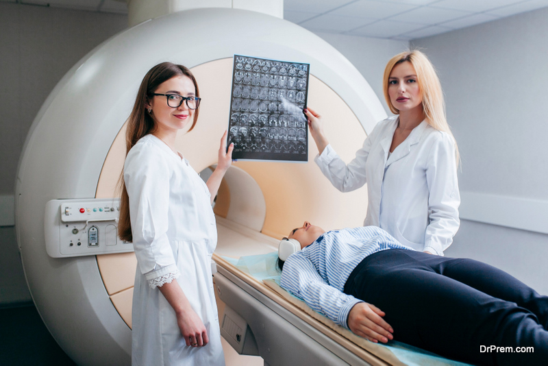 Two female models doctors examining patient and hold a picture in their hands after CT scan test