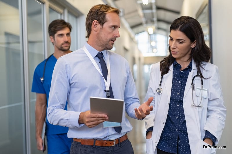 Man and woman doctor having a discussion in hospital hallway while holding digital tablet