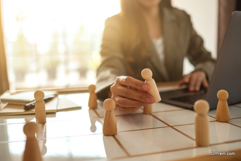 Businesswoman leader choosing wooden people from a group of employees on a planning board