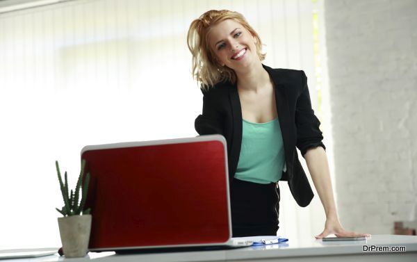 Young beautiful smiling woman leaning on the table in office