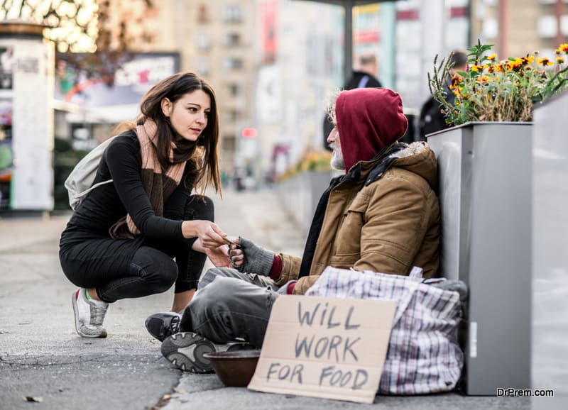 Young woman giving money to homeless beggar man