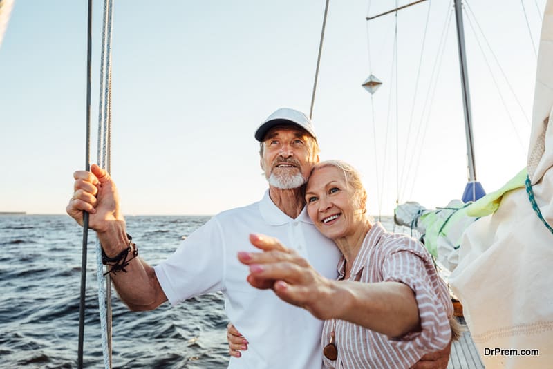 Happy mature woman pointing into the distance while embracing by her husband on their yacht