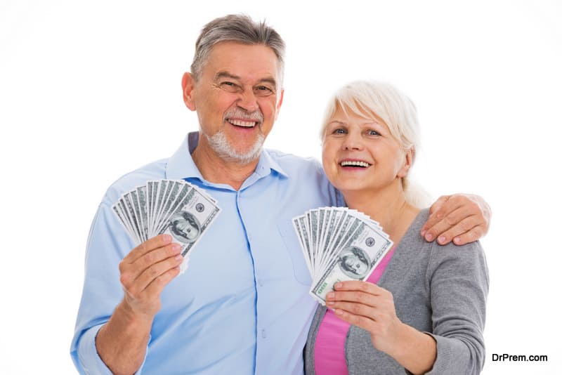 Happy senior couple standing over white background holding dollars