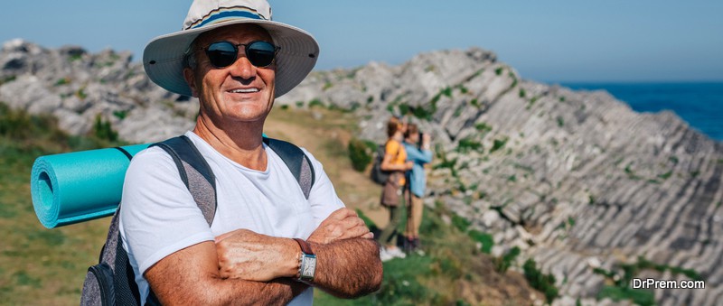 Happy senior man who practices trekking looking at camera