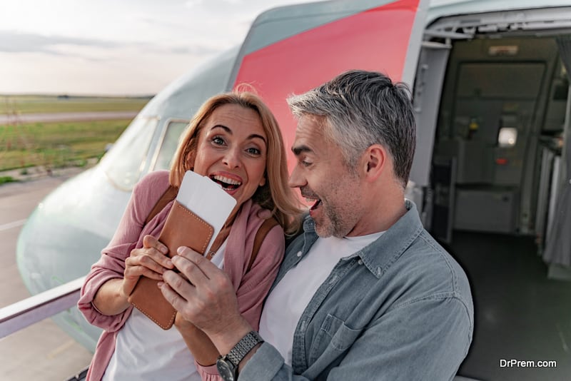 Happy woman and man holding tickets near plane 