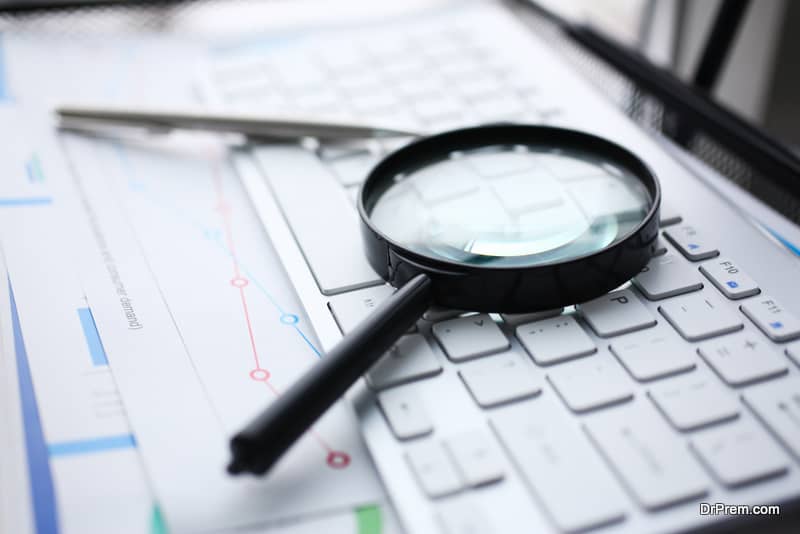 Magnifying glass lies on white keyboard on desk 