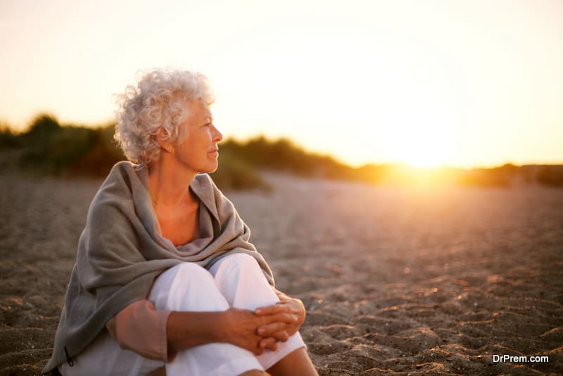 Old woman sitting on the beach looking away at copyspace