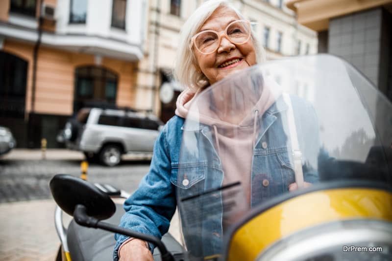 Smiling elderly female is enjoying journey on motorcycle through city