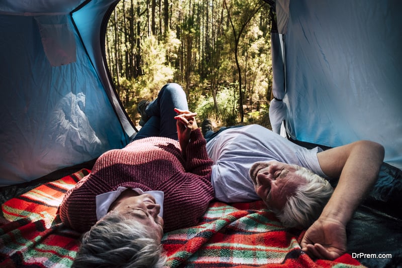 adult senior couple rest lay down inside a tent in free wild camping