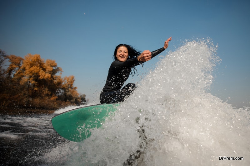 Brunette girl jumping on the green wakeboard on the bending knees