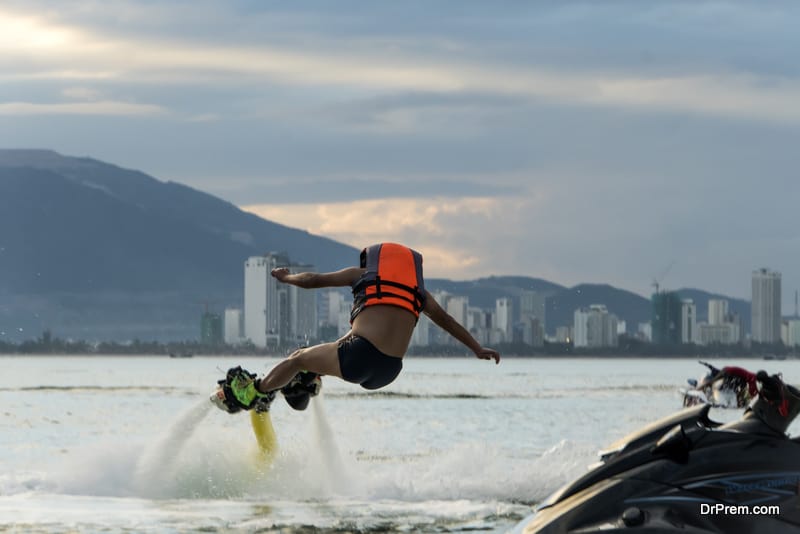 Man posing at new flyboard at tropical beach at sunset.