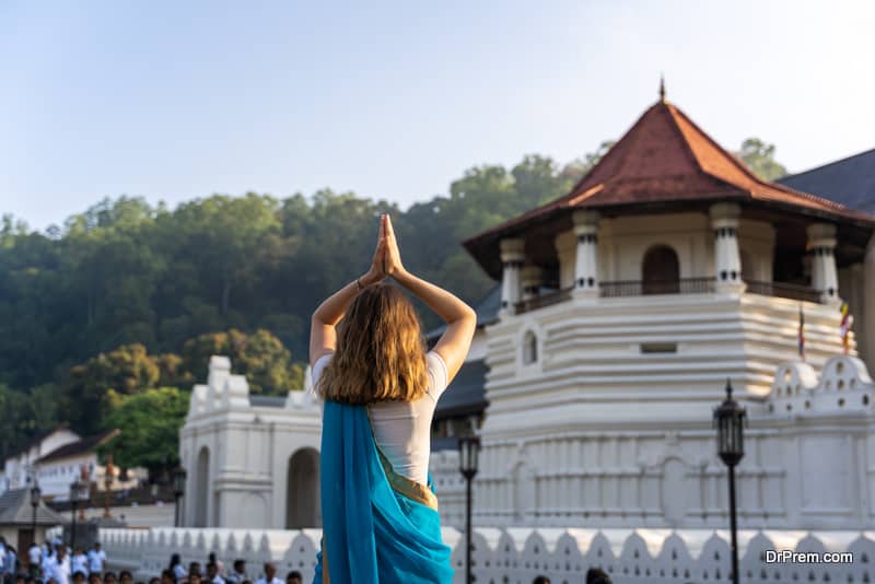 caucasian young woman is praying in front of Sri Dalada Maligwa temple