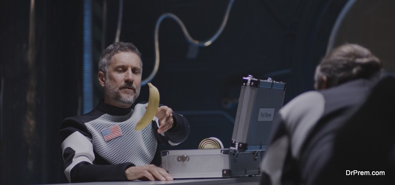 Medium shot of an astronaut pushing a banana through the air in zero gravity to his comrade