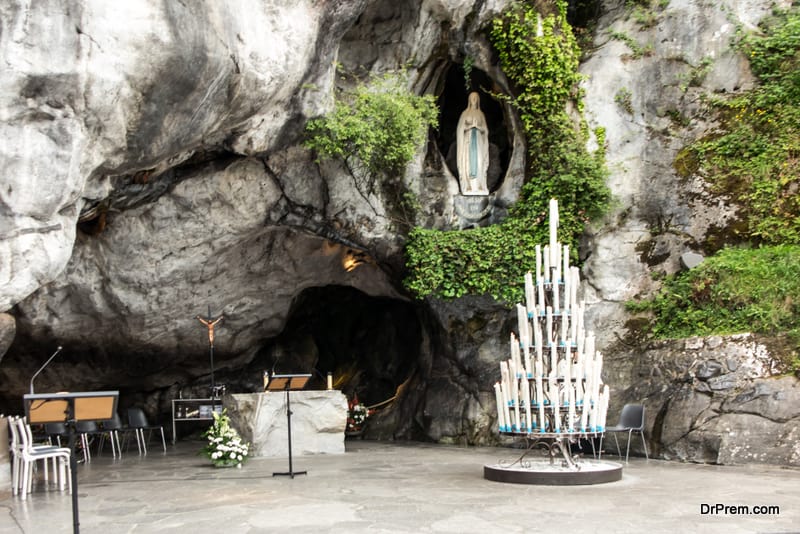 Statue of Our Lady of Immaculate Conception with a rosary in the Grotto of Massabielle in Lourdes