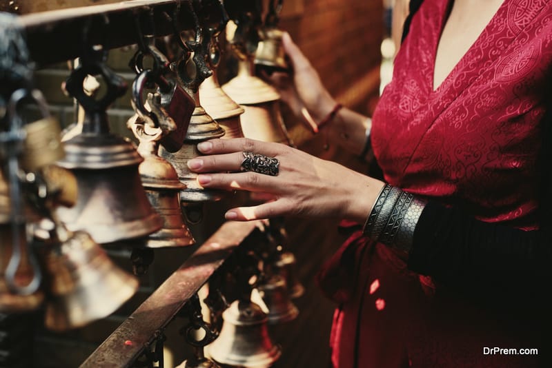 Woman hand touching buddhist bells in Nepali temple