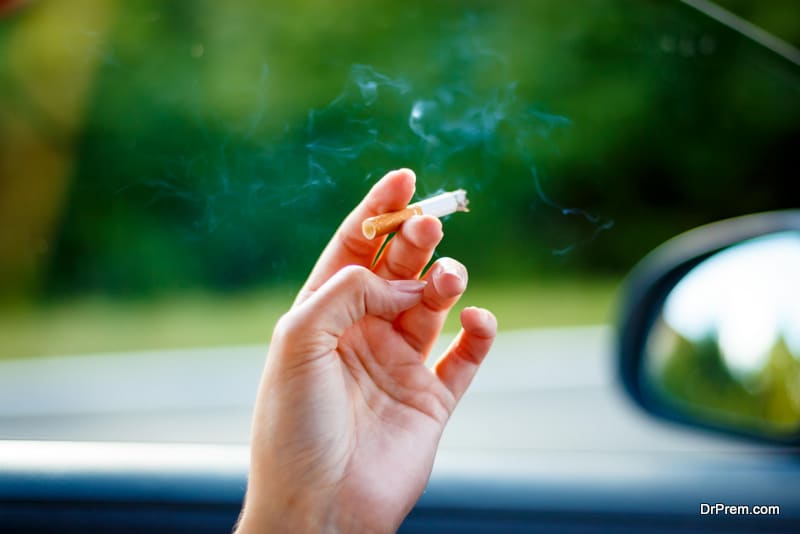 Woman smoking a cigarette at the wheel of a car.