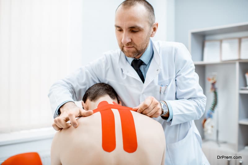 Senior therapist applying kinesio tape on a man's neck during the medical treatment in the office