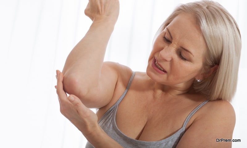 Woman with pain in arm, elbow. Pain in the human body, health care concept. Close up.
