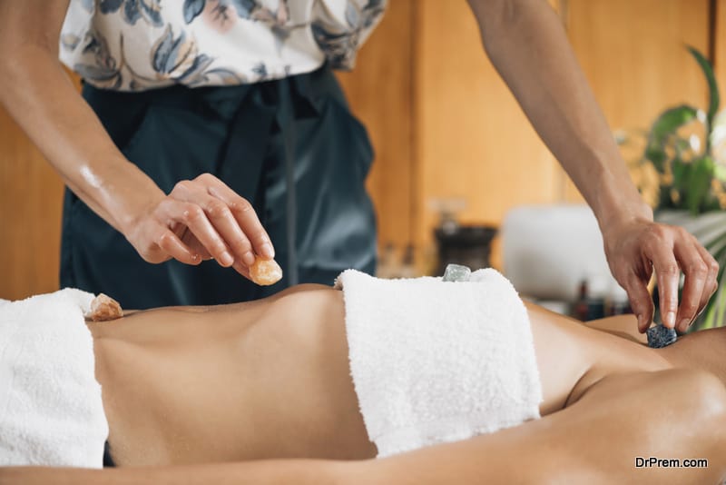 Ayurvedic practitioner using gemstones and crystals for healing female patient chakras