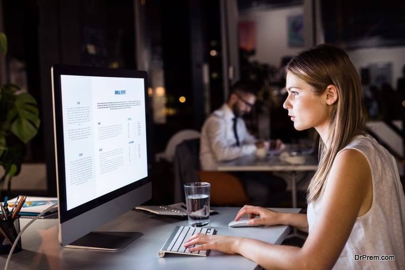 Beautiful young businesswoman in the office with her coworker at night working late.