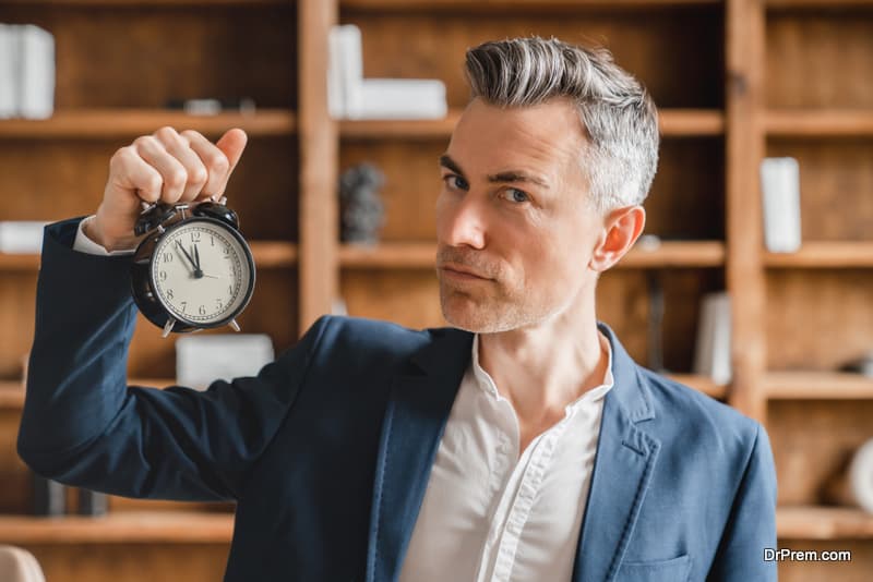 Deadline. Caucasian mature middle-aged businessman boss ceo employee freelancer holding watch clock showing time, high time for start-up in office