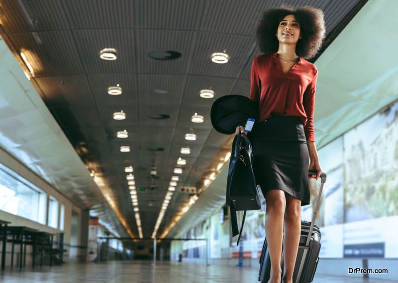 Low angle view of a businesswoman with luggage walking towards plane boarding gate.