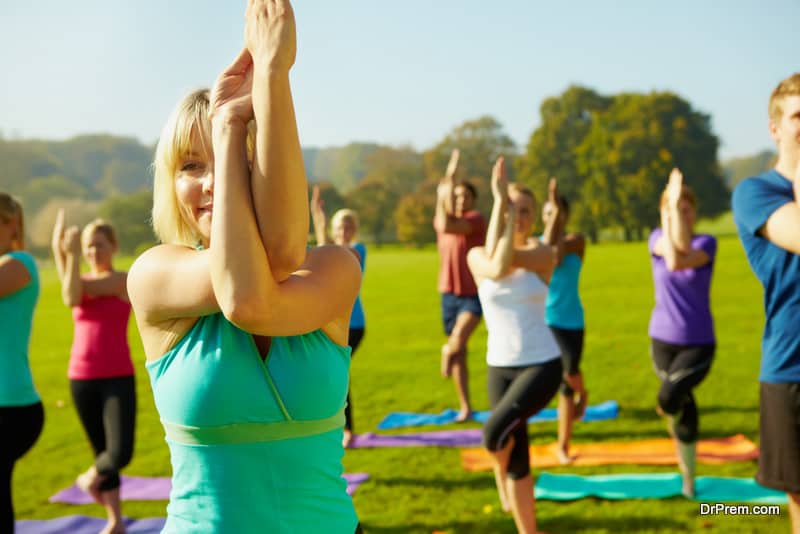 Young female yoga instructor teaching a yoga session with students in the background