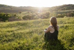 13443666-beautiful-young-woman-sitting-on-the-grass-watching-sunset-surrounded-by-green-nature