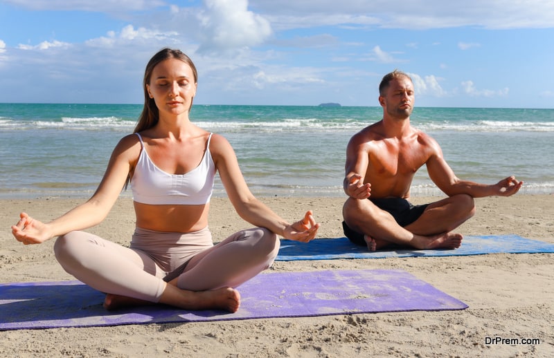 Woman and man doing yoga with lotus position on summer beach