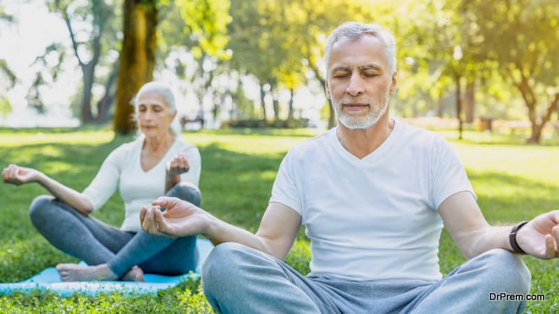 Yoga at park. Senior couple sitting in lotus pose on green grass in calm and meditation