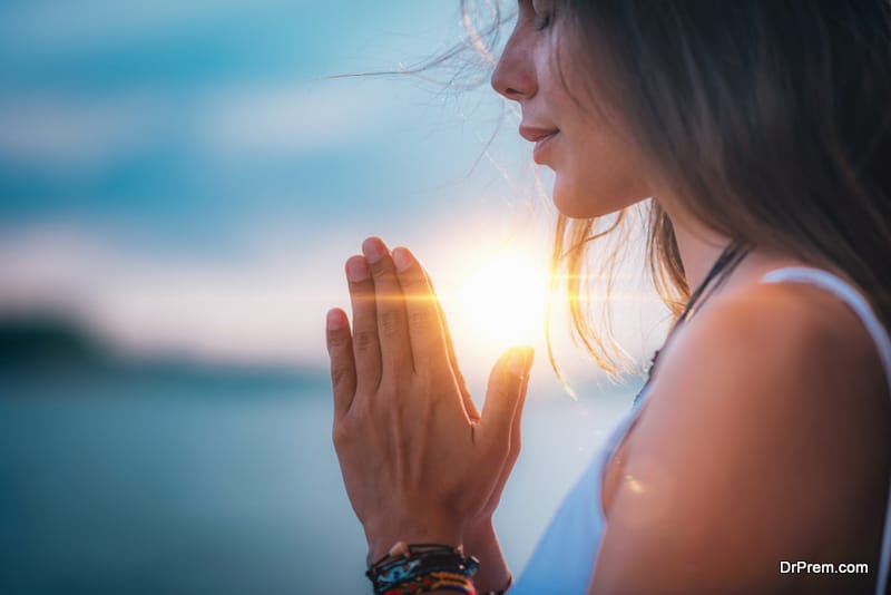 Young woman meditating with her eyes closed, practicing Yoga with hands in prayer position.