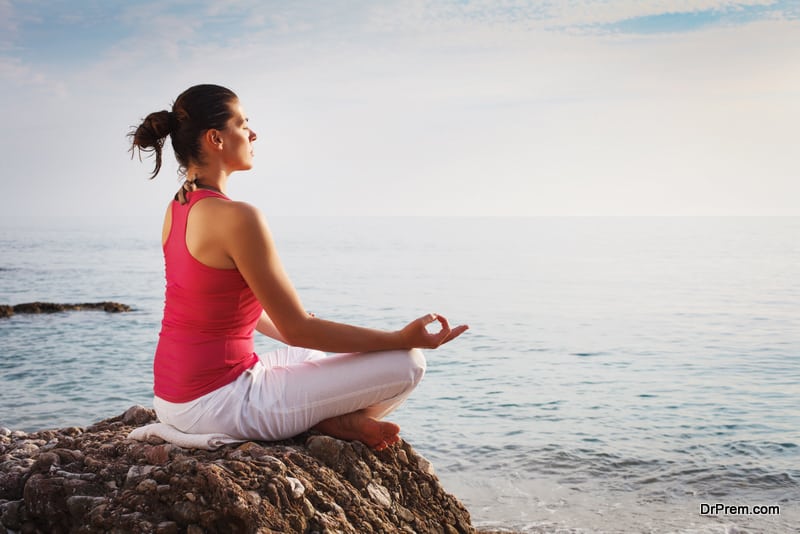 Young woman practising yoga at the beach.