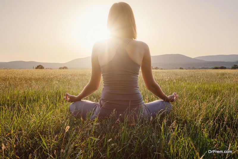 woman practices yoga and meditates in the lotus position on the field. Healthy lifestyle and Yoga concept.