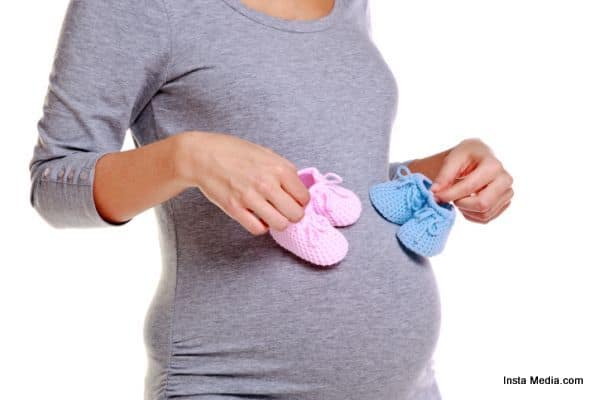 Pregnant woman holding baby booties.