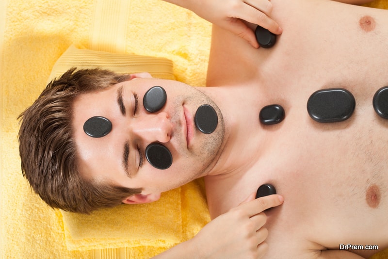 Directly above shot of handsome man receiving hot stone therapy in spa