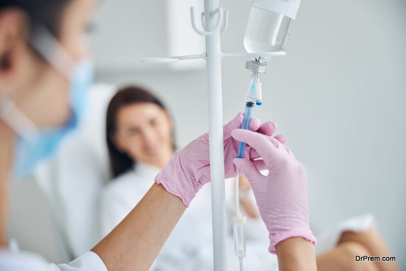 Experienced Caucasian heath care worker preparing a dark-haired female patient for the intravenous vitamin therapy